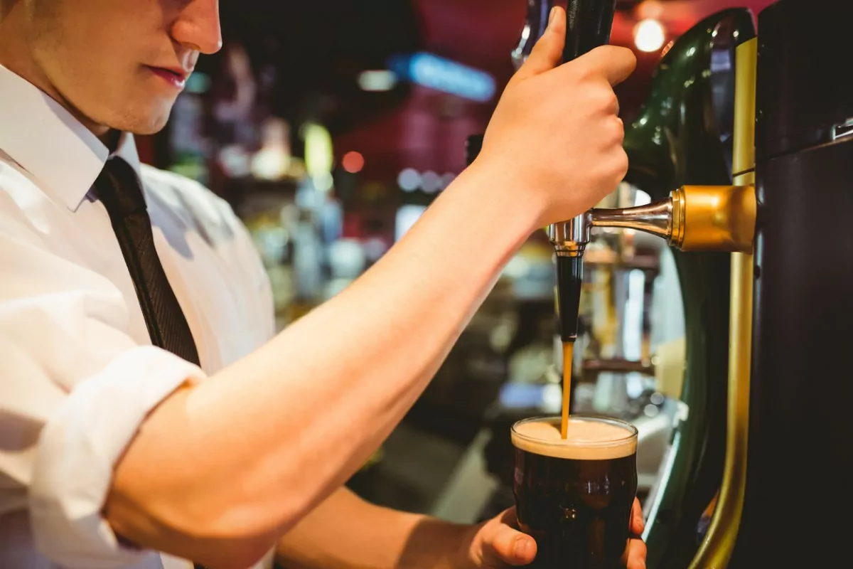 garçom servindo cerveja escura em um pin na Irlanda