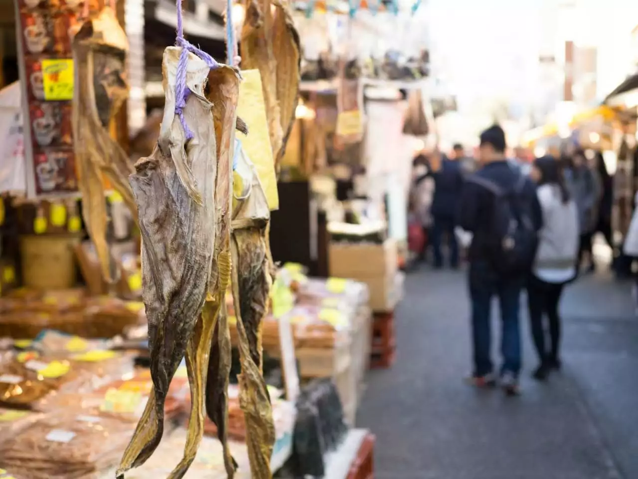 Conheça os melhores lugares para visitar no japão - detalhe de peixe seco pendurado no mercado Tsukiji no Japão e turistas ao fundo