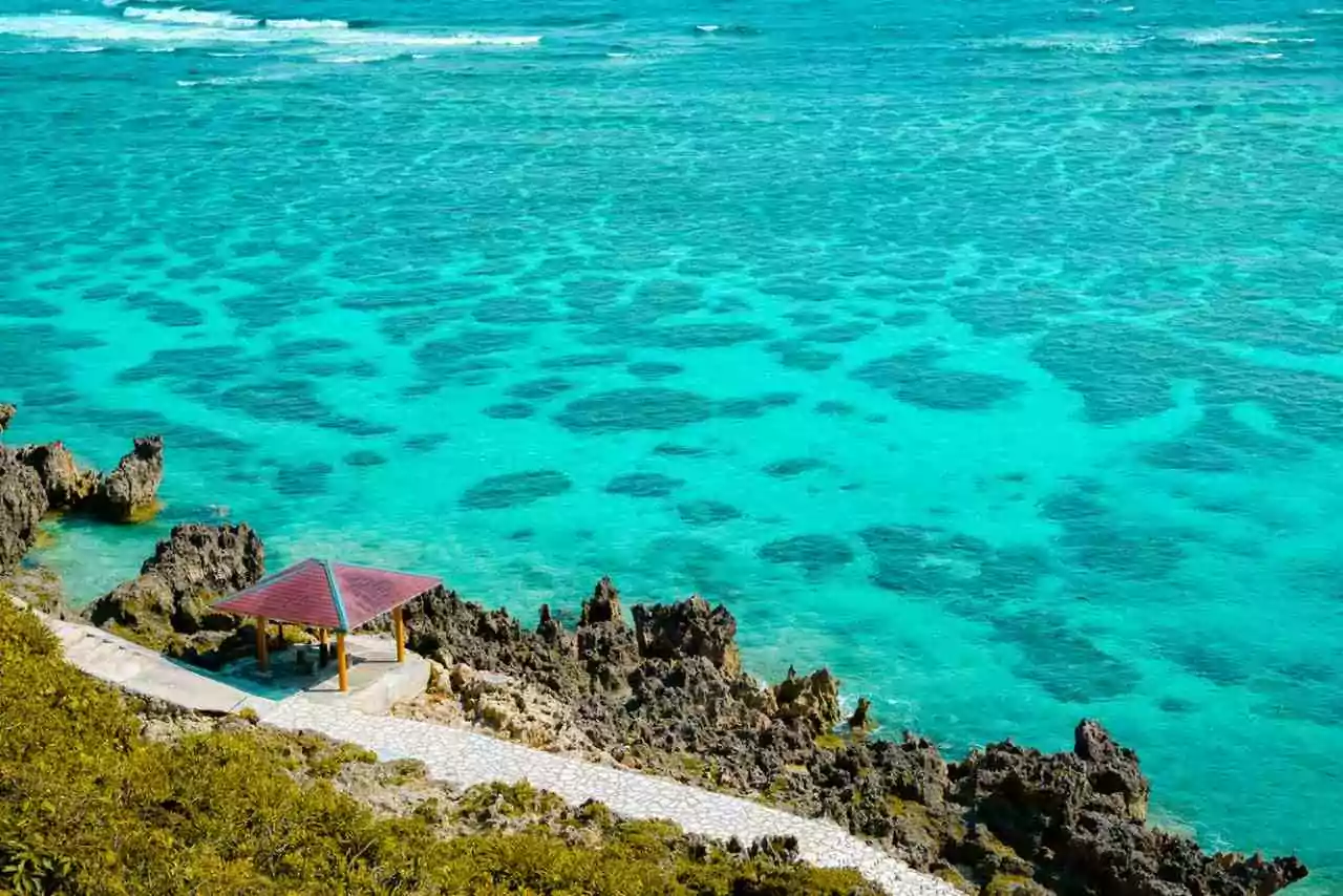 Conheça os melhores lugares para visitar no japão - Okinawa com mar azul turquesa e caminho à beira mar, com rochas 