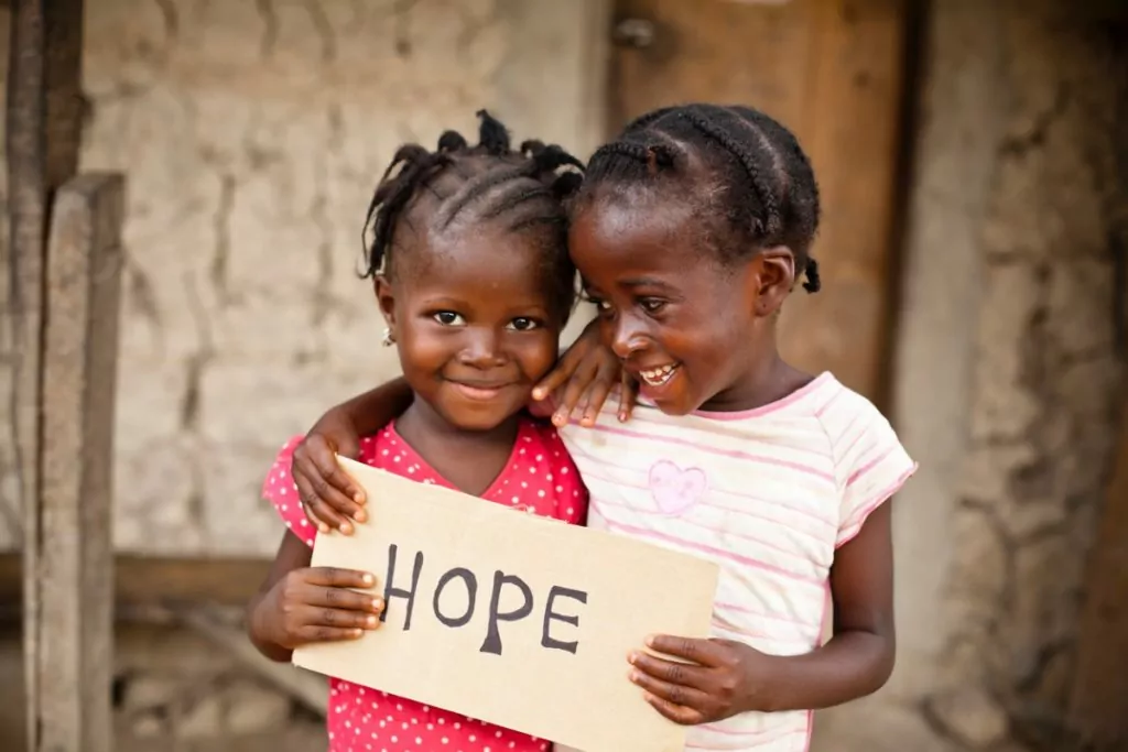 duas meninas africanas segurando cartaz escrito hope