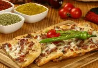 Gastronomia e Doces Turcos — 14 Delícias que Você Não Pode Deixar de Provar! Pedaços do tradicional pão turco, achatado, lembrando pizza.