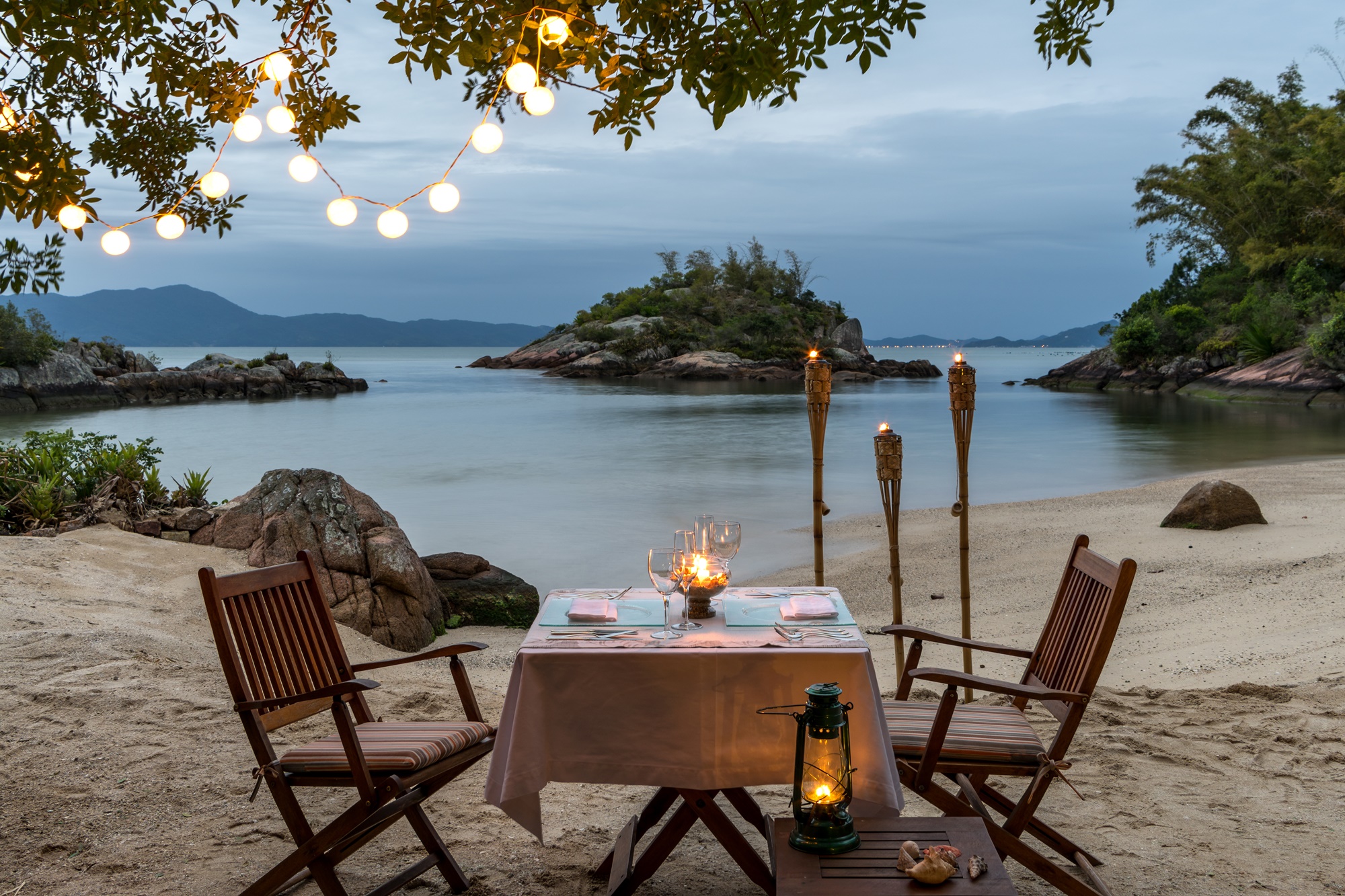 Mesa de jantar na praia, decorada com velas.