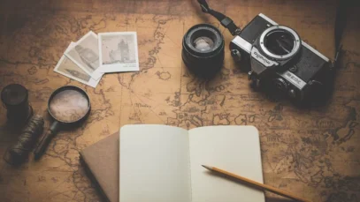 viajar-em-segurança-agentes-de-viagem Viajar em segurança. Imagem mostra mapa aberta com caderno de anotações, máquina fotográfica e lupa.