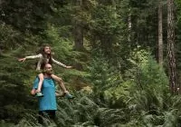Pai e filha em meio à floresta em uma viagem com criança.