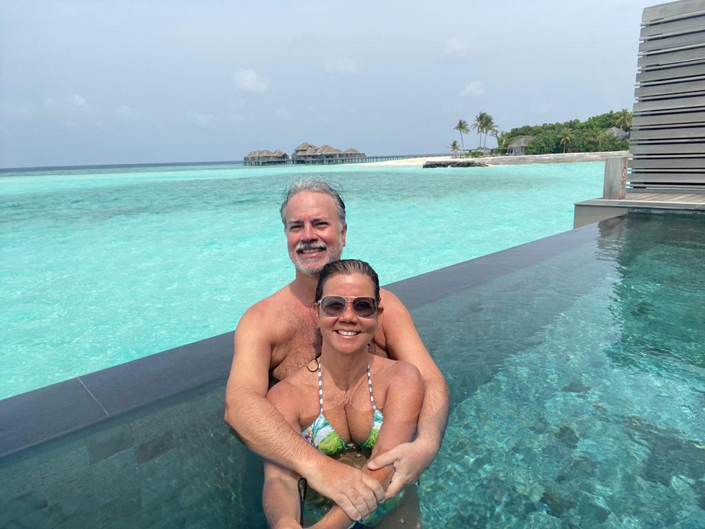 O que mudou nas viagens. Casal posa abraçado em uma piscina. Ao fundo, o mar azul cristalino das Ilhas Maldivas.