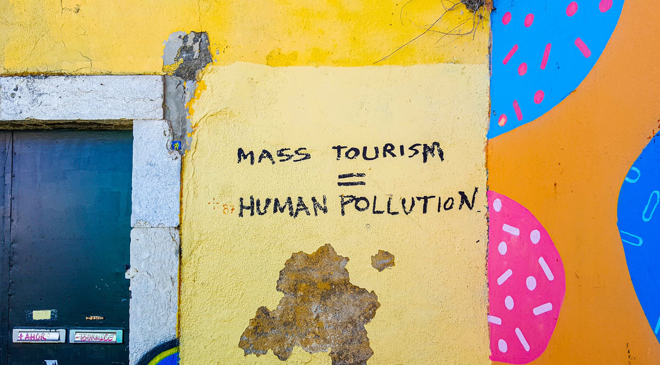 Overturismo. Muro com escrito que diz que o turismo de massa é a poluição humana.