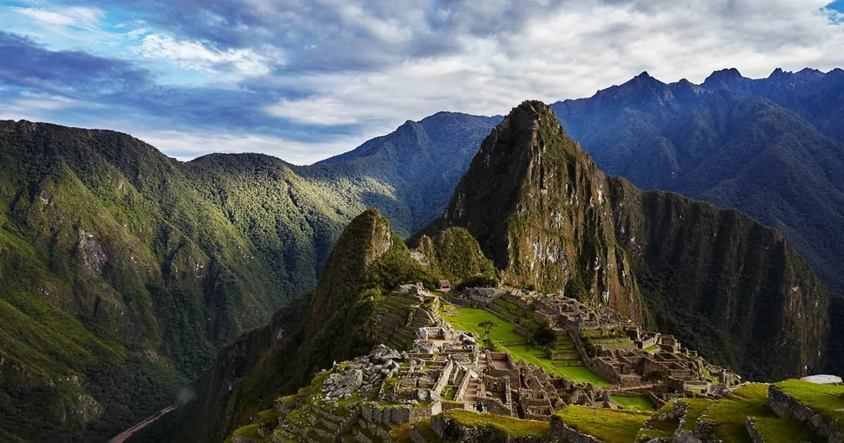 Peru, Machu Picchu à frente, entre outras montanhas, com céu nublado.