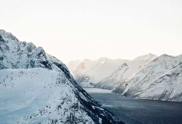 Fiordes noruegueses: um trecho de água em um corredor entre montanhas cobertas de neve.