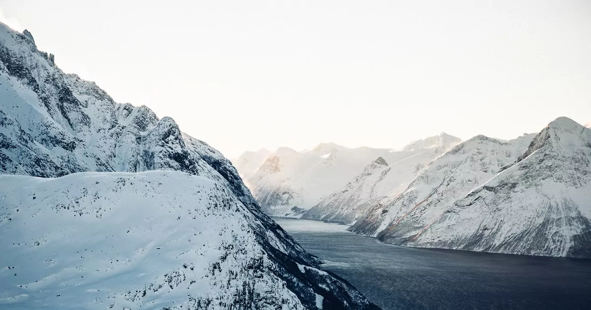 Fiordes noruegueses: um trecho de água em um corredor entre montanhas cobertas de neve.