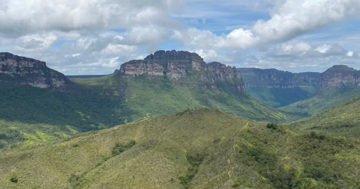 Um vale coberto de vegetação está níveis de altura abaixo das montanhas que se erguem a sua volta. Ao fundo, o céu nublado no Vale do Pati.