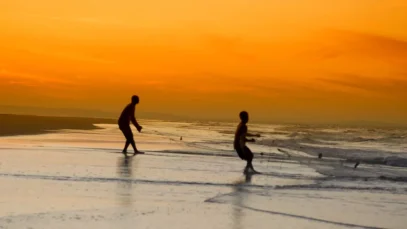 Areias douradas, mar cristalino e ilhas exclusivas fazem de Moçambique um dos destinos mais surpreendentes do Oceano Índico. Garotos manuseiam rede de pesca nas praias de Moçambique, com sol se pondo ao fundo, alaranjado.