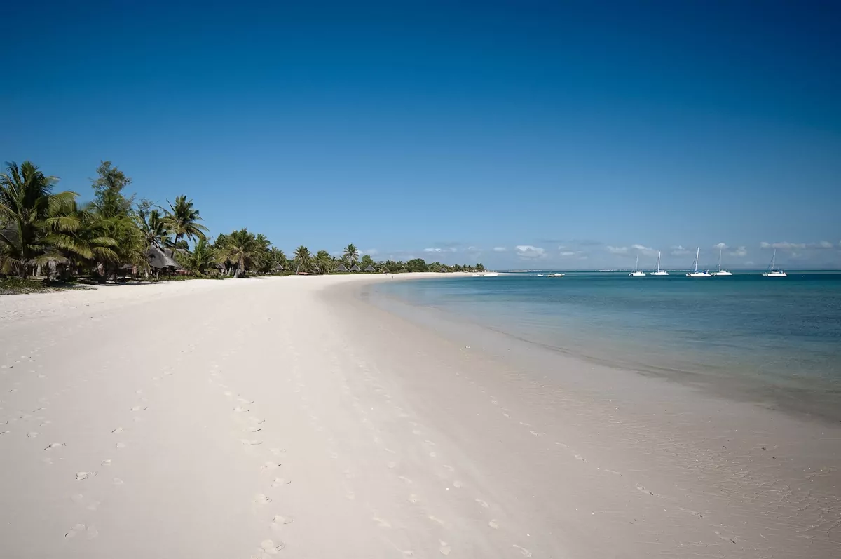 Praia de Moçambique, com areia clara e céu azul.