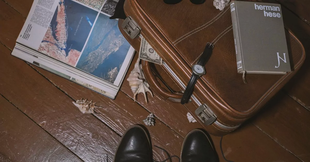 Mala, passaporte e mapa simbolizam homem se preparando para uma viagem de luxo.