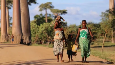 viagem-segura-africa Mulheres caminham pela avenida de baobás de mãos dadas com criança. Viagem segura na África.