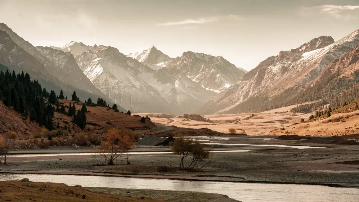 quirguistao-rio-montanhas Imagem de uma paisagem com um rio e montanhas ao fundo.