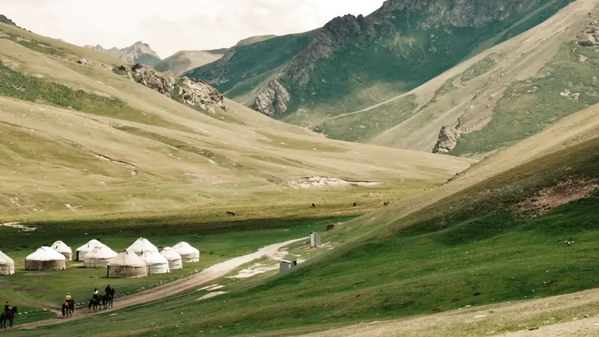 quirguistao-yurtas Imagem de uma paisagem rodeada por montanhas e um acampamento de yurtas.