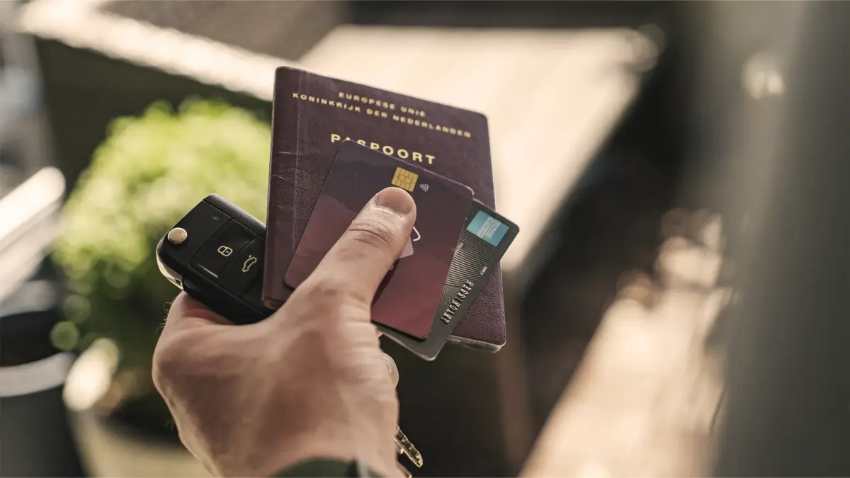 dirigir-no-exterior4 Homem segurando passaporte, chave do cartão e cartão de crédito.