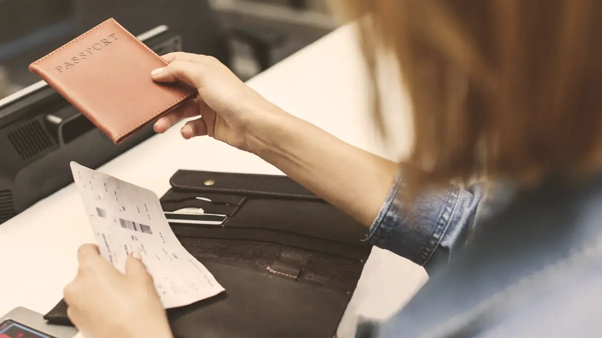 documentos-para-viagem-internacional3 Viajante entregando o passaporte em um balcão de atendimento.