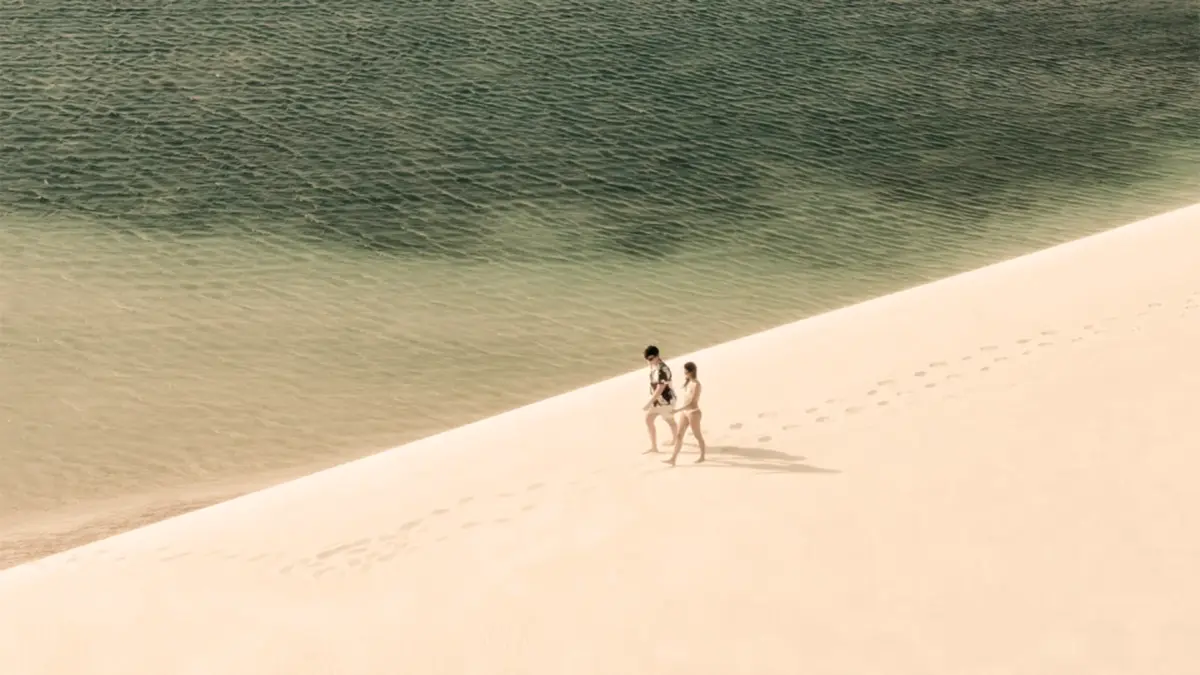 Casal caminhando próximo a uma lagoa nos Lençóis Maranhenses.