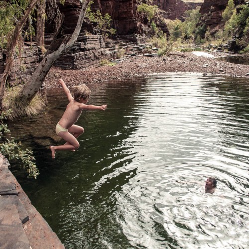 Father and son enjoying a refreshing dip in a gorge in Karijini National Park, Australia