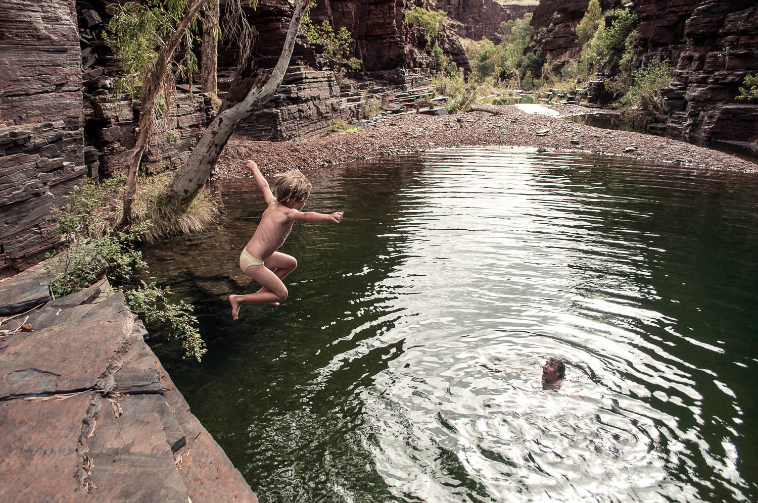 Father and son enjoying a refreshing dip in a gorge in Karijini National Park, Australia